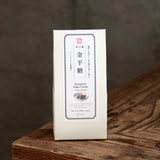 A white rectangular package of Japanese konpeito sugar candy stands upright on a rustic wooden surface against a dark gray background.